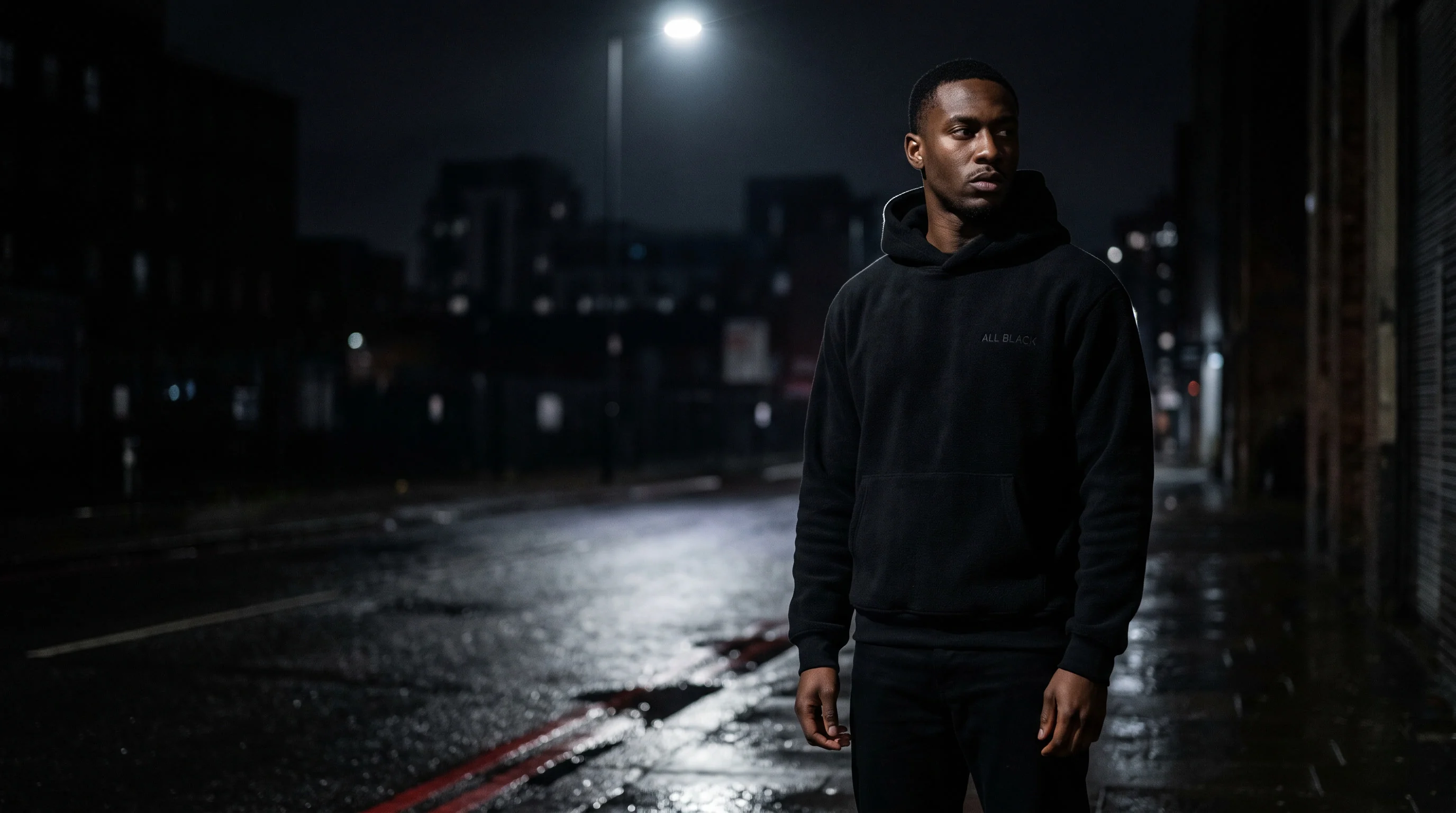 Model in a black hoodie on a wet street at night
